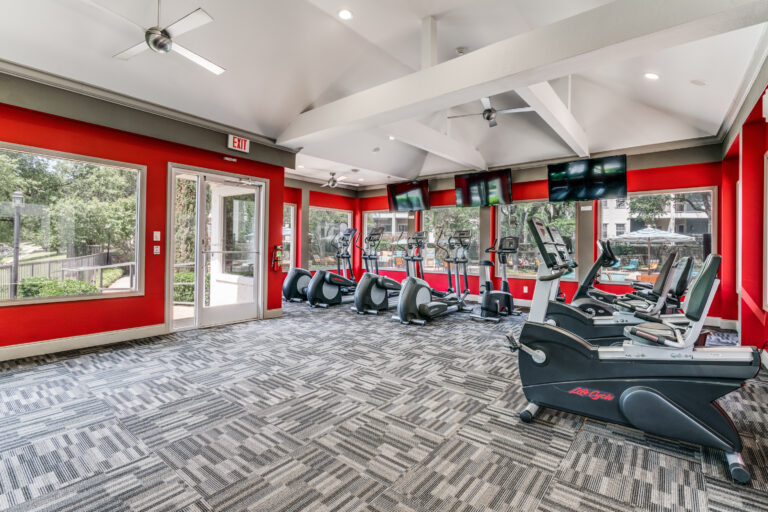 Gym with large windows, tvs, multiple sitting bikes and elliptical machine 