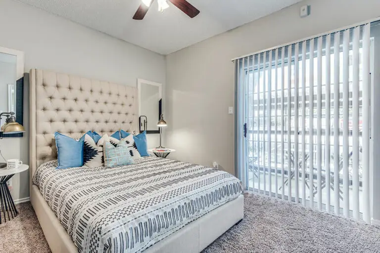 Bedroom with entrance to balcony with queen bed and two night stands