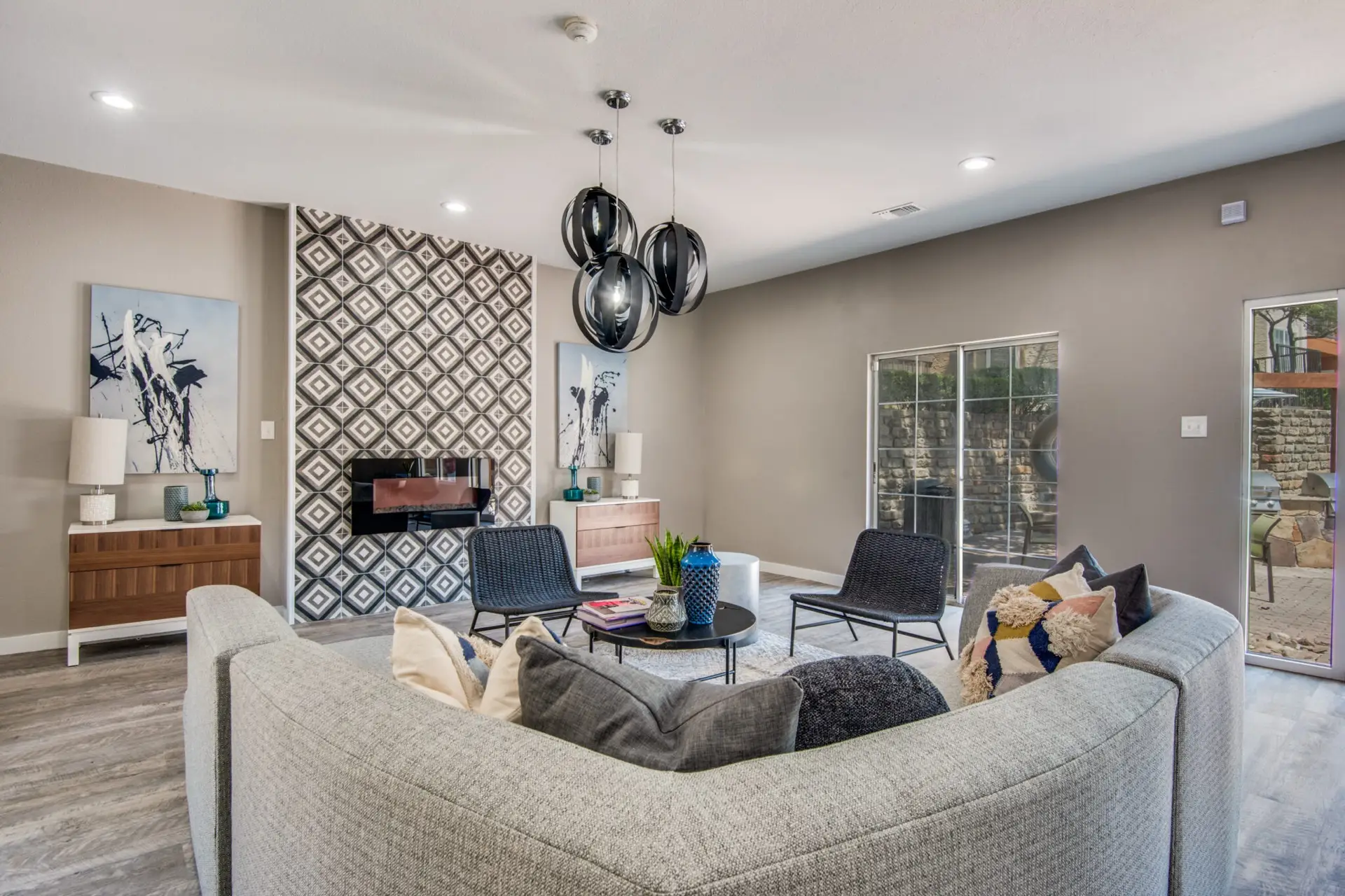 large room with designer pendant light fixture, large plush couch, and modern rectangular fireplace